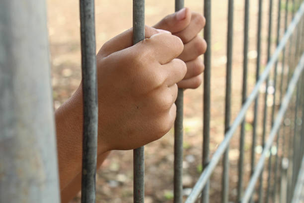 istock hand holding an iron fence or prison 2185547343