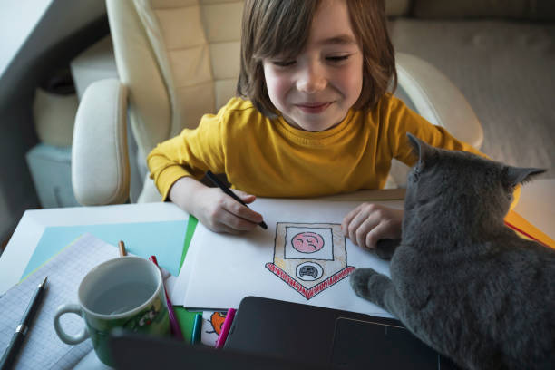 istock Smiling little boy with cat watching an online art and craft tutorial 2185548689