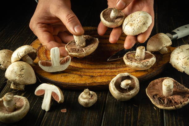 istock Sorting champignon mushrooms by male hands on a kitchen board after picking in a meadow. Concept of preparing a mushroom dish on a kitchen table 2185549334