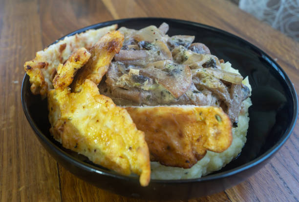 istock A dish with mushroom sauce and fried chicken meat in a black plate. Mashed potatoes covered in mushroom sauce with fried chicken 2185550253