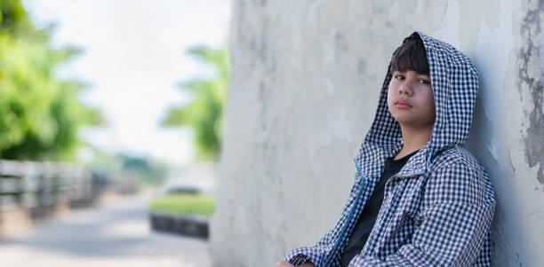 Portrait of young asian boy who has broken family, homeless, living, sleeping and standing beside rural road, sunlight edited, concept for social problems of young people around the world.