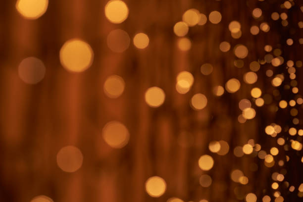istock Soft golden bokeh lights on a dark brown background creating a cozy, warm, and elegant visual effect. 2185567457