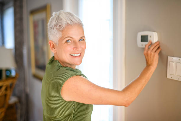 istock senior lady posing at home portrait close to a window using thermostat 2185568646