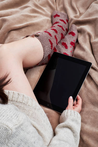 istock Woman on bed with heart socks and tablet 2185571866