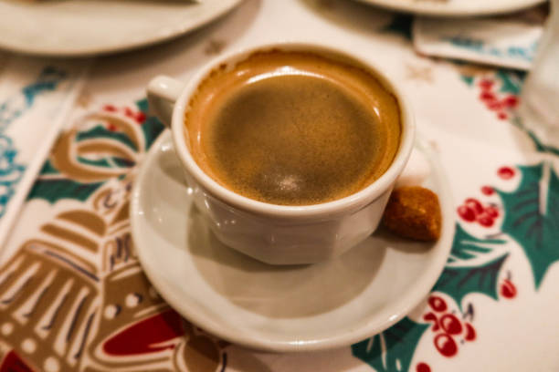 istock hot black coffee with foam on top with a brown sugar on the side on a table cloth with Christmas red and green pattern 2185574621