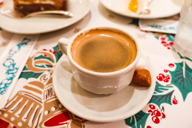 istock hot black coffee with foam on top with a brown sugar on the side on a table cloth with Christmas red and green pattern 2185574643