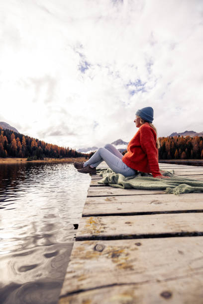 istock Woman Relaxing on a Dock by a Scenic Mountain Lake 2185576159