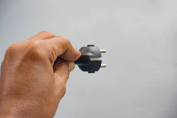 Hand holding a single plug of electric cable
