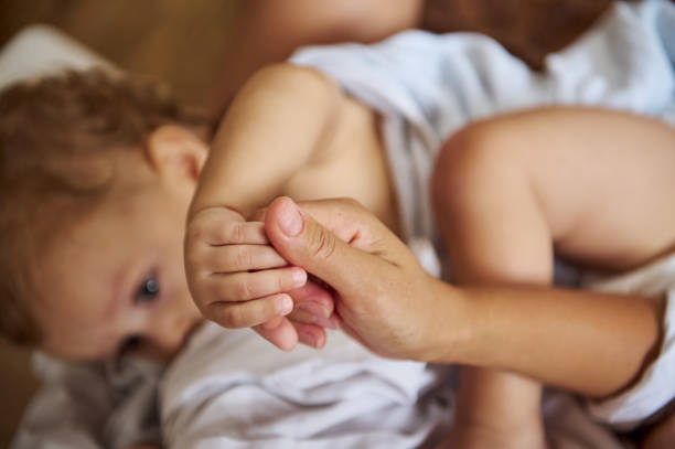 istock Tender moment between mother and baby holding hands in bed 2185582389
