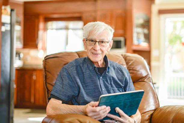 Portrait of retired senior man standing at home using tablet