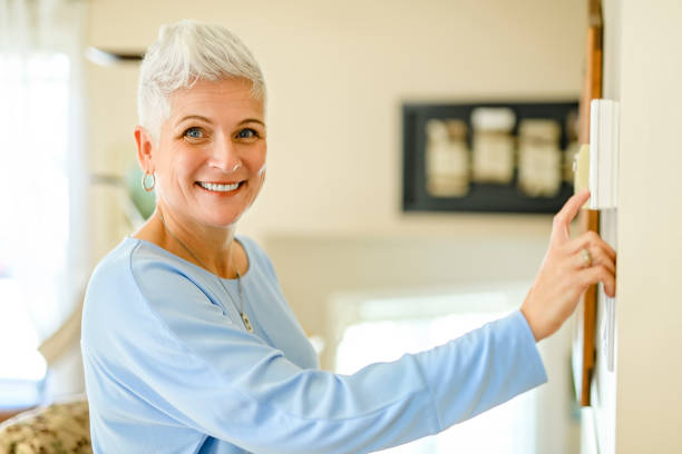 istock Senior woam using Heating Thermostat At Home In Energy Crisis 2185584749