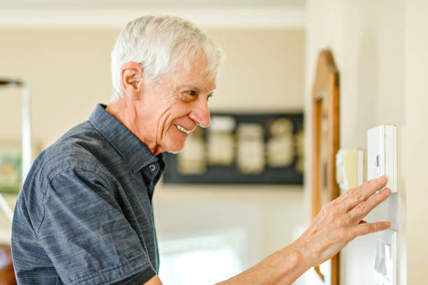 istock Senior Man using Heating Thermostat At Home In Energy Crisis 2185584751
