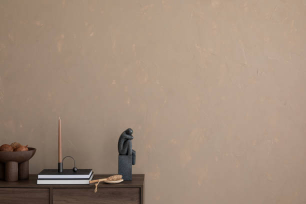 istock Minimalist interior with a textured beige wall, modern sculptures, and a unique candle holder on a wooden sideboard. Perfect blend of earthy tones and contemporary decor. Template. Copy space. 2185585101