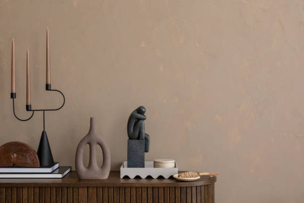 istock Minimalist interior with a textured beige wall, modern sculptures, and a unique candle holder on a wooden sideboard. Perfect blend of earthy tones and contemporary decor. Template. Copy space. 2185585164