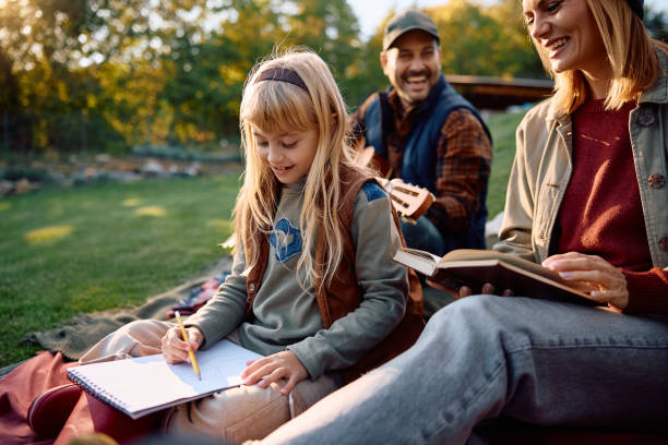 istock Happy girl drawing while spending a day in nature with her parents. 2185585290