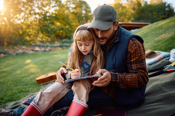istock Little girl and her father drawing while relaxing in the park. 2185585330