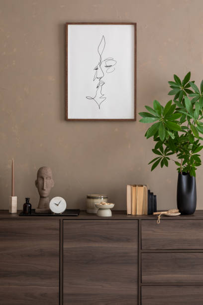 istock Minimalist Living Room Setup. Cozy commode with a minimalist design against a neutral-toned wall, complemented by modern décor. Suitable for contemporary interior design themes. Mock up poster. 2185585376
