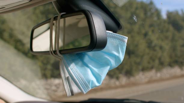 istock A face mask is currently hanging from the rear view mirror of a car 2185587020