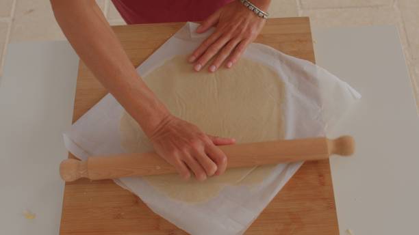 istock A person is rolling out dough with a pin on a wooden table 2185587836