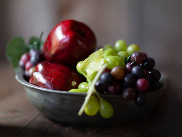 A closeup photo of fresh black grapes in a red bowl