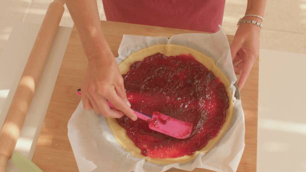 istock A person is spreading raspberry jam on a pie with a spatula 2185588109