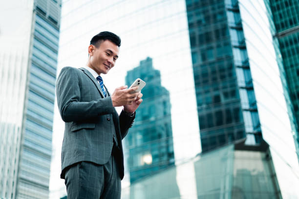 istock Asian man looking at his phone in a modern urban environment 2185588885