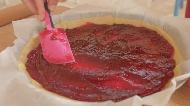 istock A person is carefully spreading jam on top of a pie using a spatula 2185589074