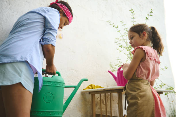 istock Mother and daughter watering plants on a sunny day 2185589868