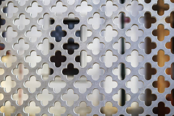 gray metal mesh with holes behind which there is a window in the background