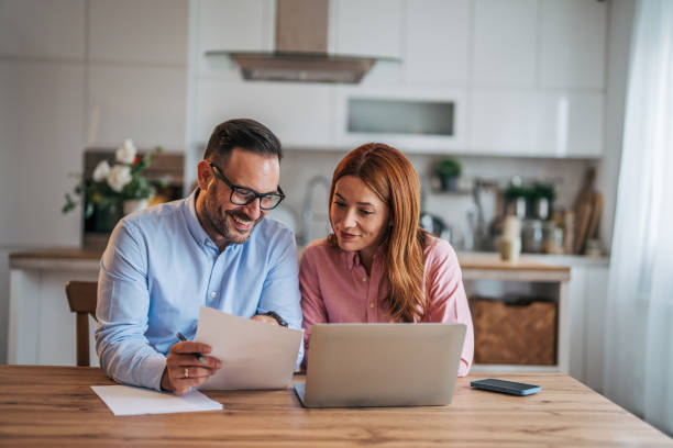 istock A married business couple in the kitchen using a laptop at the table. 2185596684
