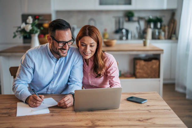 istock A married business couple in the kitchen using a laptop at the table. 2185597250