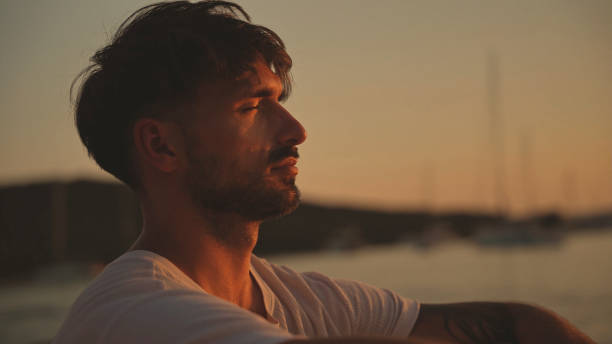 istock Man Relaxing by the Sea at Sunset 2185597636