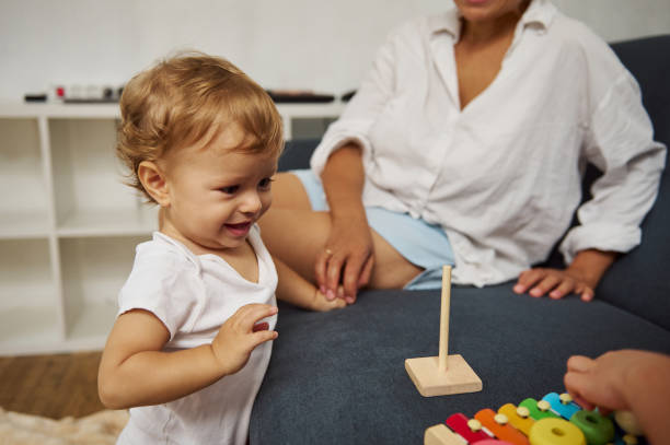 istock Curious toddler exploring toys with parental supervision on couch 2185597966