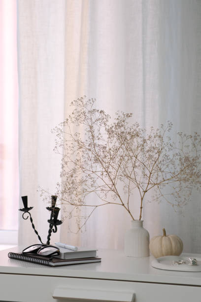istock Stylish autumn decor that beautifully features dry flowers, a minimalistic pumpkin, notebooks, glasses next to window. 2185599761