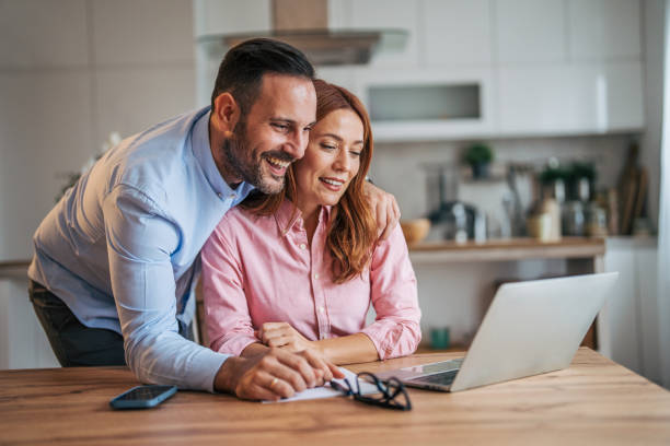 istock A married business couple in the kitchen using a laptop at the table. 2185601003