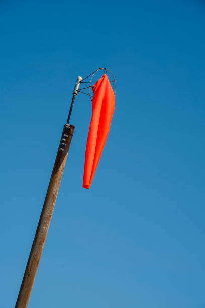 Red wind flag (windsock) in calm conditions with blue sky background Wind sleeves show wind direction and speed. Windy weather concept.