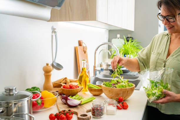 istock Mature woman preparing lettuce salad using fresh ingredients 2185603200
