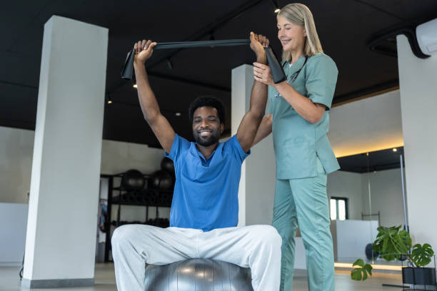 istock Young african american man exercising with a stretch band during rehabilitation session 2185603992