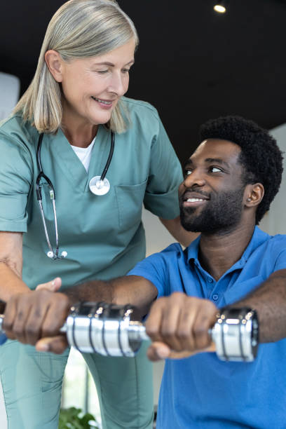 istock Young male patient exercising with dumbbells with a physical therapist 2185604009