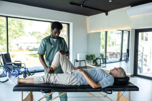 istock Female patient lying on a couch while male doctor working on her legs stretching 2185604124