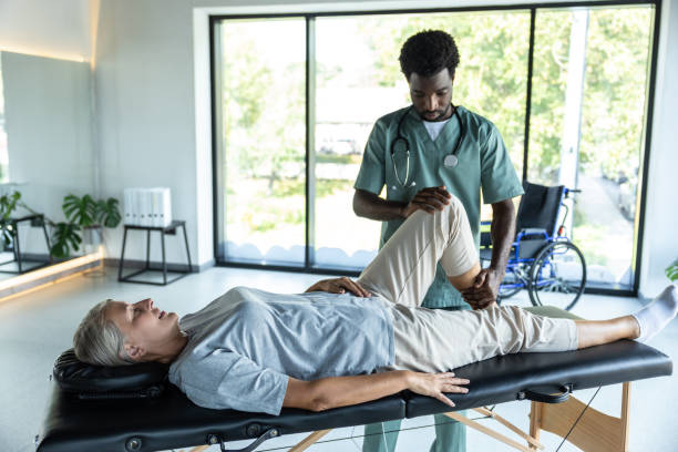 istock Female patient lying on a couch while male doctor working on her legs stretching 2185604125