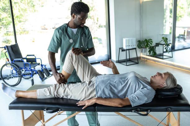 istock Female patient lying on a couch while male doctor working on her legs stretching 2185604131