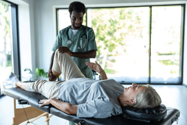 istock Female patient lying on a couch while male doctor working on her legs stretching 2185604137