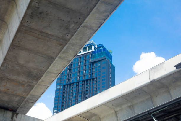 Apartment tower with small rooftop garden seen between BTS skytrain bridges in Bangkok Ladprao / Chatuchak