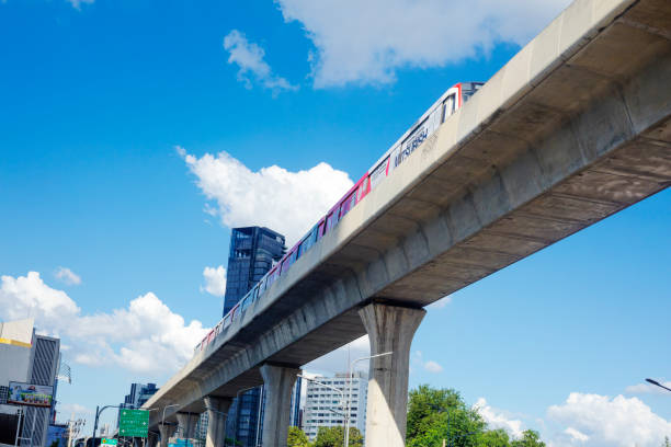 New BTS skytrain line at Phahoyothin Road with passing train. View from street level. Scene is between Central Ladprao and junction Ratchadaphisek Road. Some buildings and apartment towers are in sky and skyline