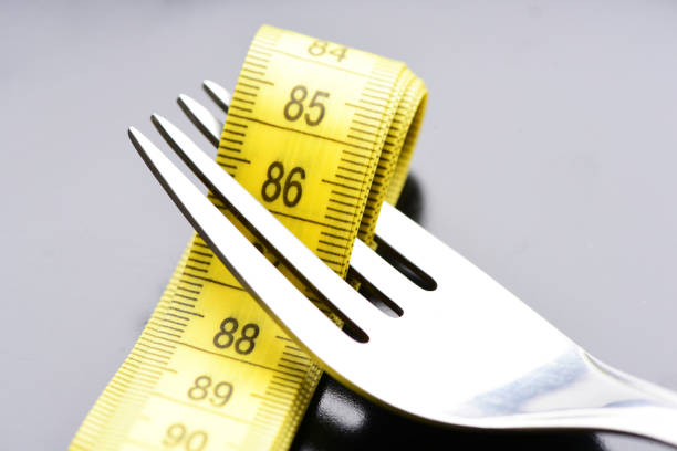 istock Fork holds folded yellow tape for measuring between it's tines 2185607539