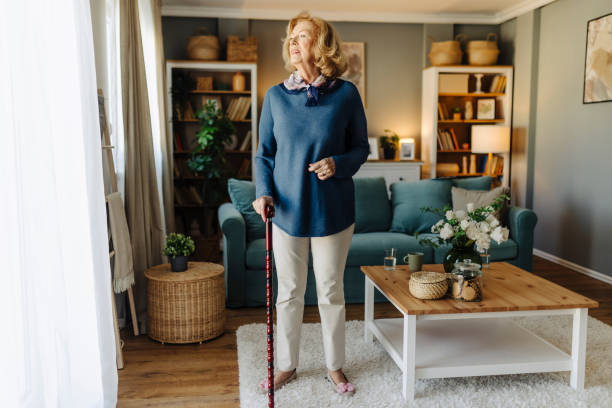 istock Senior woman standing by a window with a cane 2185607656