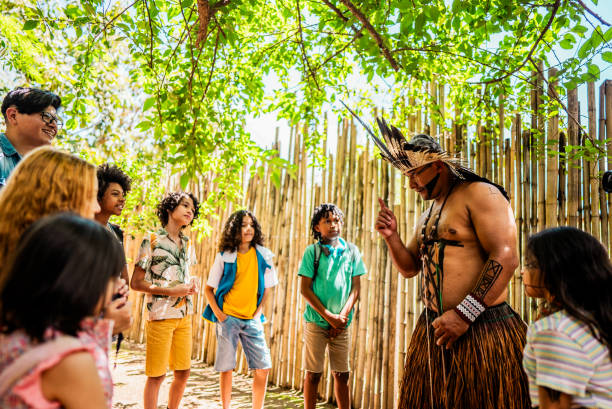 istock Indigenous man talking with children during a field trip to village 2185608443
