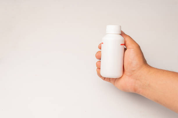 istock hand holding blank white squeeze bottle plastic tube on white background. Packaging for pill, capsule or supplement. Product branding 2185609033