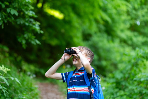 istock little boy in the forest looking through binoculars, 2185609034